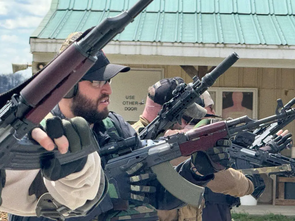 AK1 A group of men holding guns and rifles.