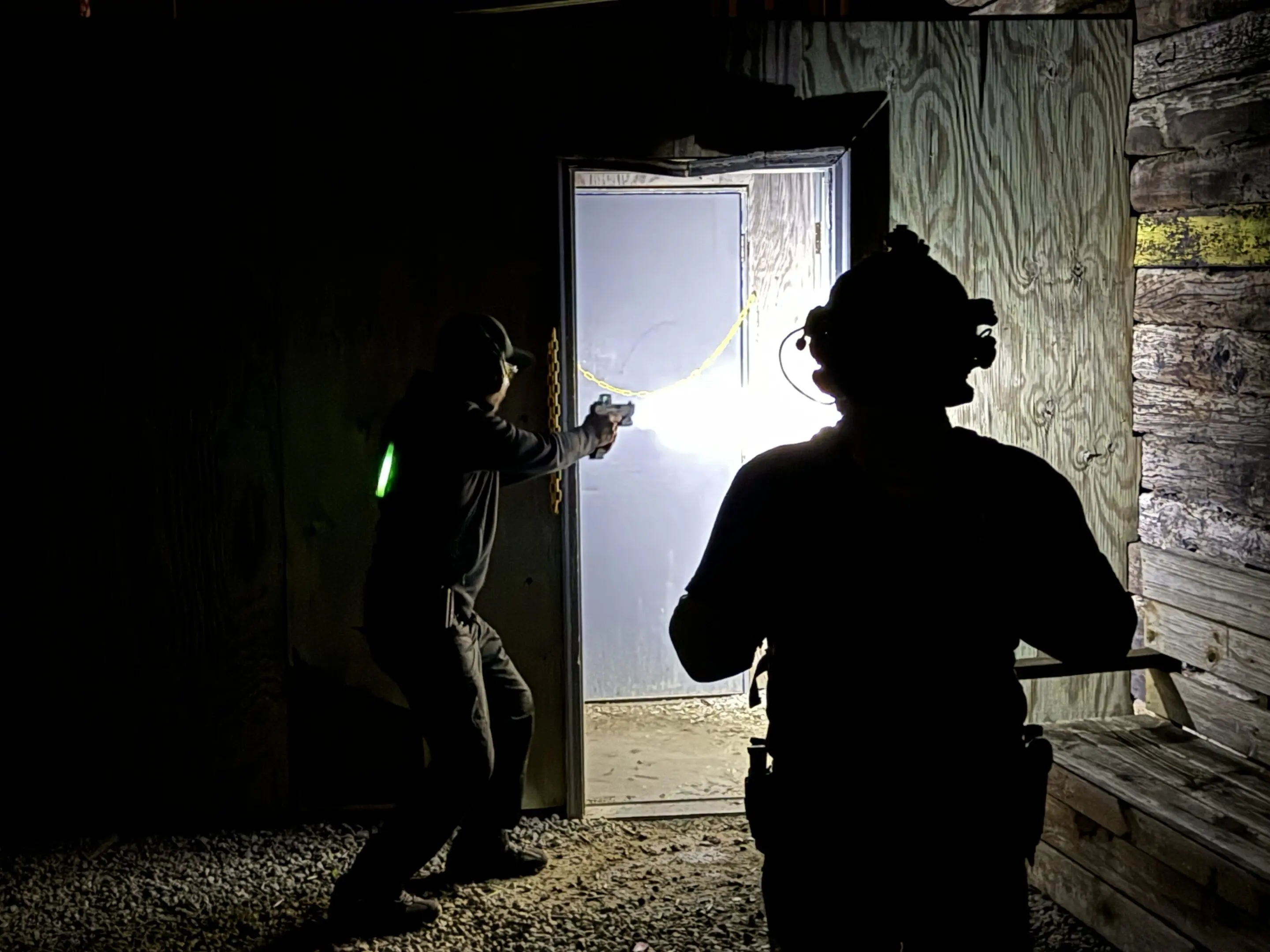 A person is holding a gun in front of a door.