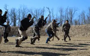 A group of men holding guns while standing on top of a field.