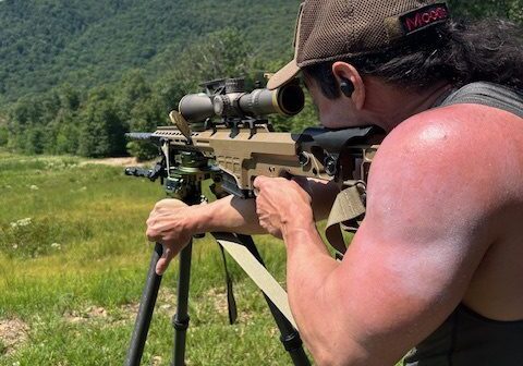 A man with a gun and rifle in the field.